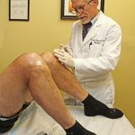 Dr. Noel Peterson administering stem cell treatment to alleviate joint pain in a patient's knee at Oregon Regenerative Medicine.