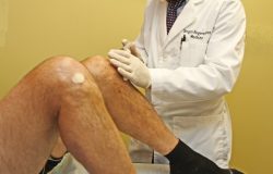 Dr. Noel Peterson administering stem cell treatment to alleviate joint pain in a patient's knee at Oregon Regenerative Medicine.