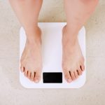 Woman standing barefoot on scale used for assessing weight loss