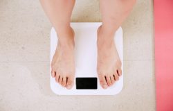 Woman standing barefoot on scale used for assessing weight loss