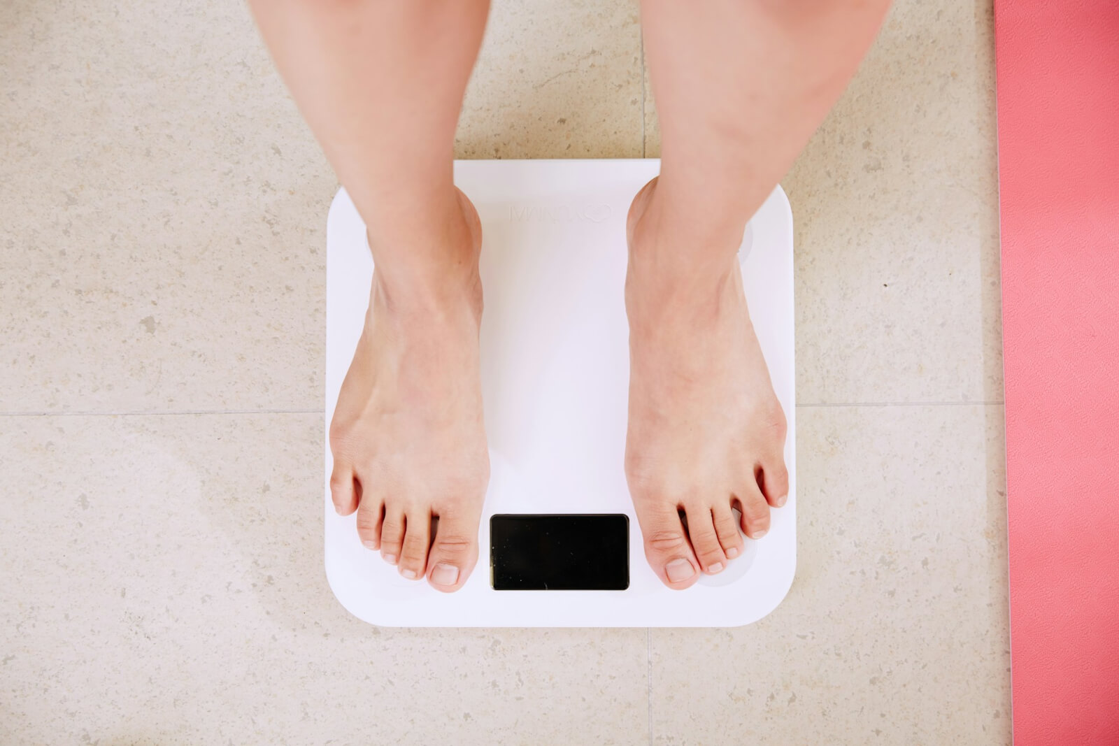 Woman standing barefoot on scale used for assessing weight loss